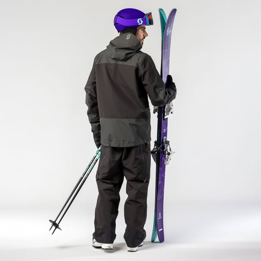 Skiing enthusiast holding skis and poles, dressed in winter gear, showcasing essential winter sports equipment for skiing adventures.