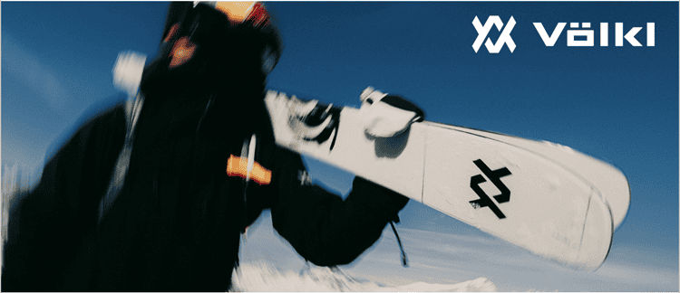 Ski enthusiast holding a snowboard in winter sports gear against a snowy mountain backdrop, representing everything winter for winter sports lovers.