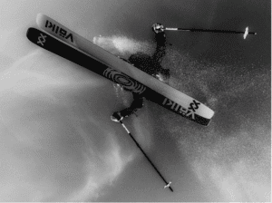 Skier performing aerial trick on snowy mountain slope, showcasing winter sports action and skills on skis.