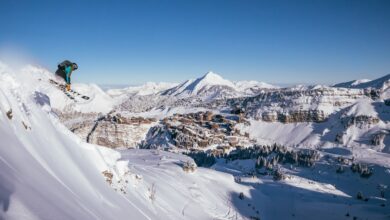 Snowboarder tackling a snowy mountain slope with a scenic winter landscape in the background.