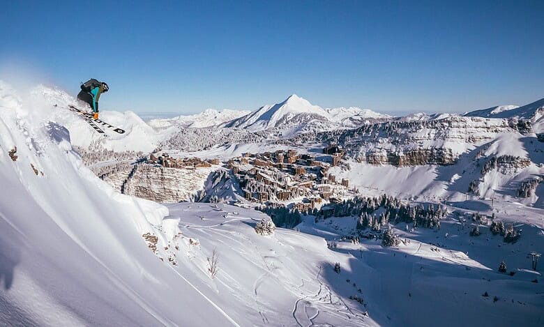Snowboarder tackling a snowy mountain slope with a scenic winter landscape in the background.