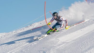 Skier navigating through a slalom gate on a snowy mountain slope during a competitive alpine skiing event, showcasing precision and speed in winter sports.