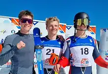 Youthful male skiers in racing gear celebrating after a winter sports competition at a snowy ski resort.