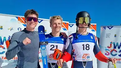 Youthful male skiers in racing gear celebrating after a winter sports competition at a snowy ski resort.