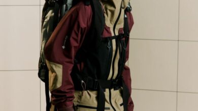 Backpacker in winter sports gear, wearing goggles and gloves, standing indoors, ready for winter adventure, showcasing premium winter clothing and equipment for snow and cold weather conditions.