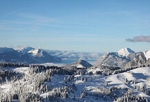 Snow-covered mountain landscape with pine forests and clear blue sky, perfect for winter sports and winter travel enthusiasts.