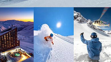 Sunny winter ski slope with skier in orange gear racing down mountain, snow-covered landscape with ski resort in background.