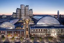 Elegant winter cityscape featuring a modern glass-roofed shopping centre with illuminated exteriors, showcasing contemporary architecture and vibrant urban life, ideal for winter trips and holiday shopping.