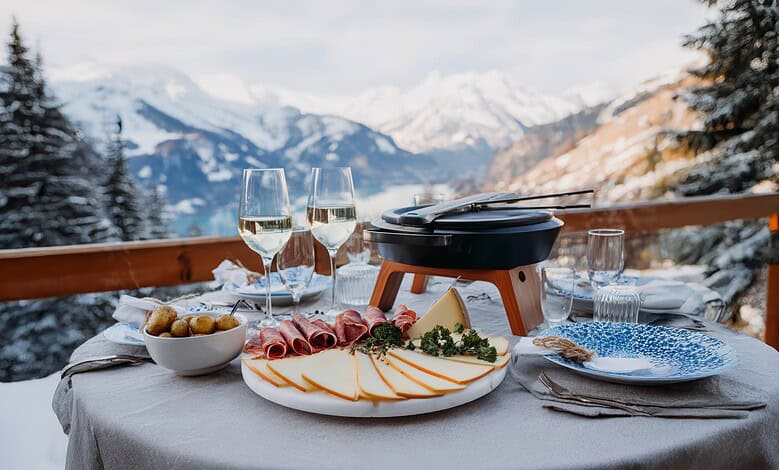 Elegant winter mountain outdoor dining setup with cheese, cold cuts, and wine in snowy Alps, perfect for winter holiday meals.