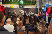 A panel discussion at a winter sports event with an engaged audience, showcasing winter fitness and outdoor gear in a retail setting.