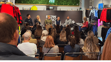 A panel discussion at a winter sports event with an engaged audience, showcasing winter fitness and outdoor gear in a retail setting.