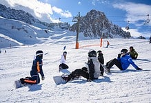 Kids snowboarding lesson on winter snowy mountain slope with ski lift and mountain backdrop, winter sports, snow activities, outdoor recreation, snow sports adventure, winter outdoor fun, skier training, learning to snowboard, mountain skiing, winter holiday activities.