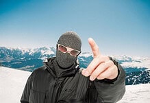 Skiers in winter gear on snowy mountain with clear blue sky, showcasing winter sports and outdoor adventure.