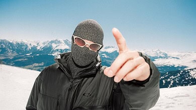 Skiers in winter gear on snowy mountain with clear blue sky, showcasing winter sports and outdoor adventure.