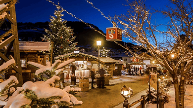 Snow-covered festive market scene with Christmas trees and holiday lighting at dusk, showcasing winter festivities and holiday shopping atmosphere.