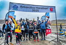 Antarctica Marathon 2025 participants celebrating at the start line, showcasing winter marathon endurance amidst icy terrain for winter sports enthusiasts.