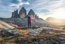 1. A hiker standing in a mountainous landscape during sunset, surrounded by rugged terrain and dramatic peaks, reflecting adventure and exploration for winter and outdoor enthusiasts.