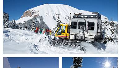 Aerial view of snow-covered mountains with skiers and snowmobile under clear blue sky, showcasing winter adventure activities; perfect content for Everything Winter enthusiasts.