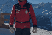 A mountain rescue expert in winter gear standing on snowy slopes with mountain peaks in the background, showcasing winter safety and rescue preparedness.