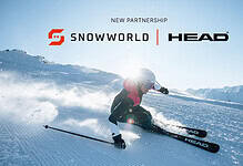 A skier in a red jacket and helmet carving through fresh snow on an indoor ski slope, showcasing HEAD's latest ski equipment in collaboration with SnowWorld Group.