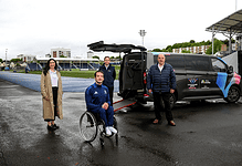 Accessible sports team with a wheelchair athlete and support staff at an outdoor stadium, showcasing winter sports equipment and inclusive athletic opportunities.