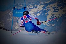 Skier racing downhill on a snowy mountain slope during a competitive event.