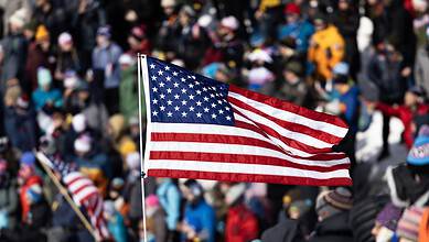 American flag waving at a crowded winter sports event with spectators in winter clothing.
