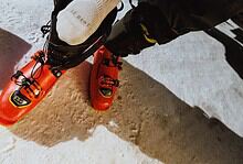 Close-up of a skier's foot wearing a Nikolai Schirmer Zero Cushion Pro Series Snow Sock and ski boot on snow.