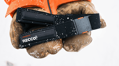 Close-up of a winter safety headlamp held in gloved hands, suitable for outdoor winter activities and snow safety.