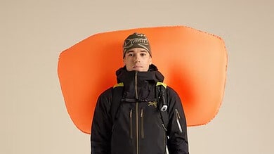 Climber with Arc'teryx Micon LiTRIC 16 avalanche airbag backpack, dressed in winter mountaineering gear, ready for snow safety in winter conditions.