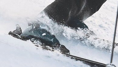 Close-up of skier's ski boots and skis in motion on snow, capturing the dynamic movement of winter sports.