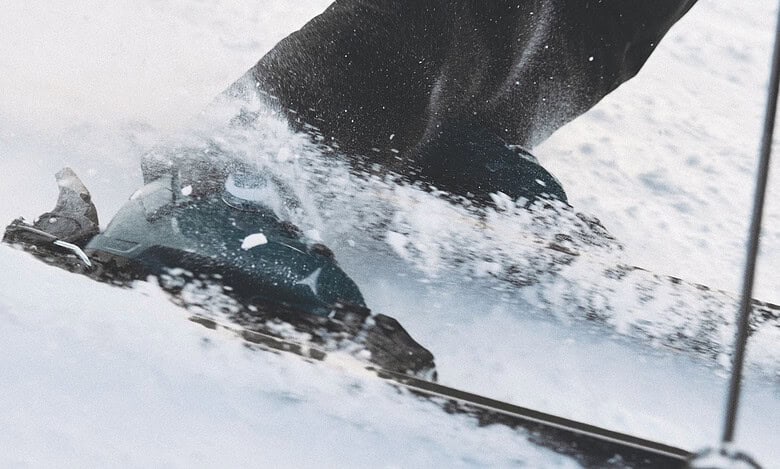 Close-up of skier's ski boots and skis in motion on snow, capturing the dynamic movement of winter sports.