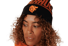 Woman wearing a black and orange knit beanie with a pom-pom and a bear mascot logo, paired with an orange hoodie.