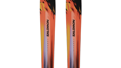 Pair of Salomon skis with vibrant orange, black, and yellow design, ideal for winter skiing adventures.